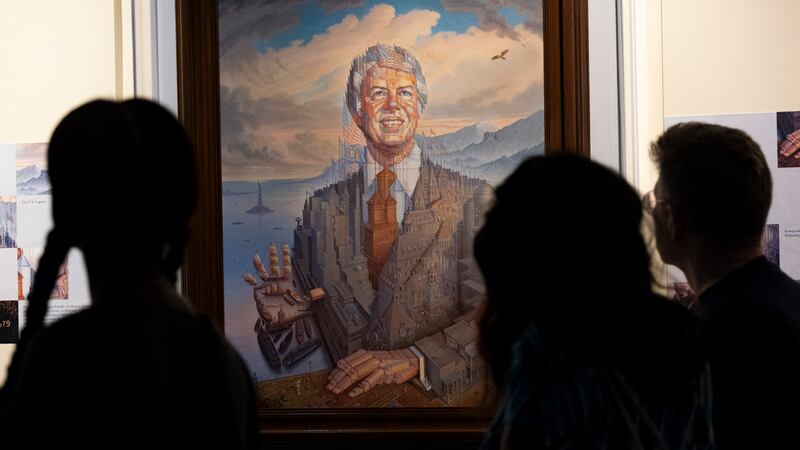 Visitantes pasan frente a un retrato del presidente Jimmy Carter durante una celebración por...