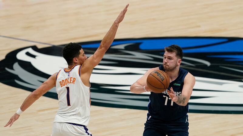 El guardia de los Dallas Mavericks, Luka Doncic (77), pasa el balón alrededor del guardia de...